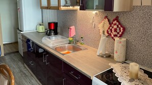 Une cuisine avec un plan de travail en bois, un évier, une machine à café et un grille-pain. On y trouve des placards et un four à micro-ondes au-dessus du plan de travail.
