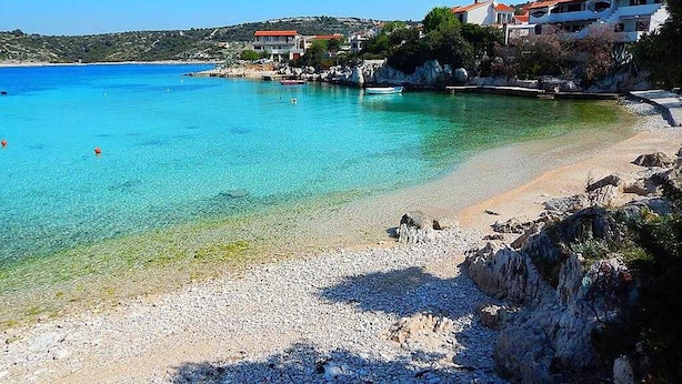 A coastal beach with clear turquoise water, rocky shoreline, and buildings with red roofs. - Gorgeous apartment in Kanica with WiFi (Kanica)