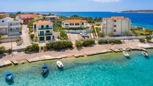 A coastal residential area with clear turquoise waters, several houses, and boats moored along the shore. - Gorgeous apartment in Kanica with WiFi (Kanica)