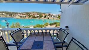 A balcony with a table and chairs overlooking a coastal town with boats and houses. - Gorgeous apartment in Kanica with WiFi (Kanica)
