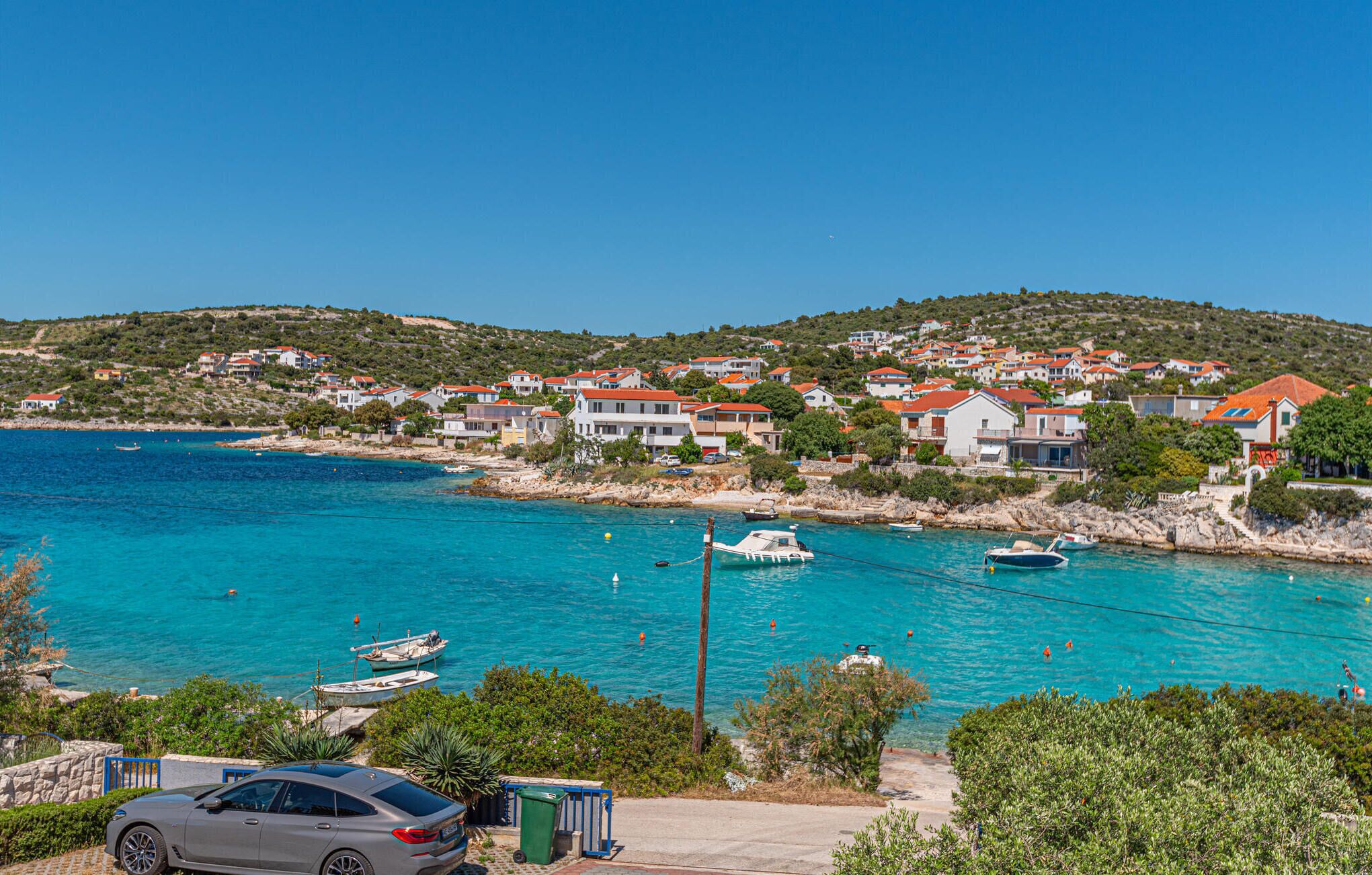 A coastal town with houses, a marina, and a parked car.
