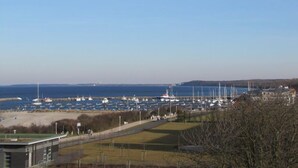 Un port esportiu amb nombroses embarcacions amarrades, una platja sorrenca i un cel blau i clar.