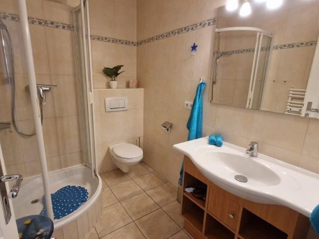 Baño con ducha, inodoro, lavabo y espejo.