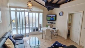 Un saló amb un sofà, una taula de centre de vidre, una televisió i un balcó amb vistes.