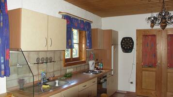 Eine Küche mit Holzschränken, einem Spülbecken, einem Herd und einem Fenster mit Vorhängen.