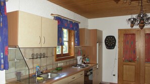 Une cuisine avec des meubles de rangement en bois, un évier, une cuisinière et une fenêtre avec des rideaux.