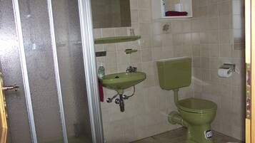 A bathroom with a shower, sink, toilet, and a mirror.