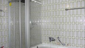 A bathroom with a glass-enclosed shower, a bathtub, and a sink.