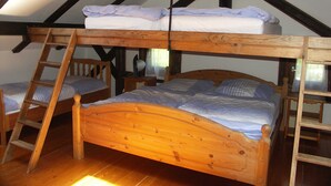 Une chambre de style « loft » avec un lit superposé en bois, une échelle en bois et une chaise en bois.