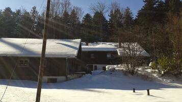 A house with a snow-covered roof and a yard with a wooden utility pole.