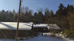 Une maison dont le toit est recouvert de neige et dont la cour abrite un poteau en bois servant de support pour les lignes électriques.