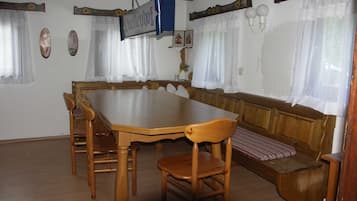 A dining area with a wooden table and benches, a hanging sign, and a window with curtains.