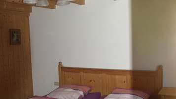 A wooden bed with a headboard, a wooden nightstand, and a ceiling light fixture.