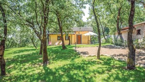 Een gele villa met pannendak, omgeven door bomen en gazon.