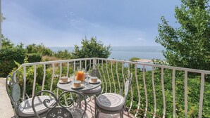 Un balcone con un tavolo apparecchiato per due, vista su un corpo d'acqua.