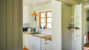 Una cocina con armarios blancos, encimera de madera, pileta, horno microondas y ventana con marco de madera.