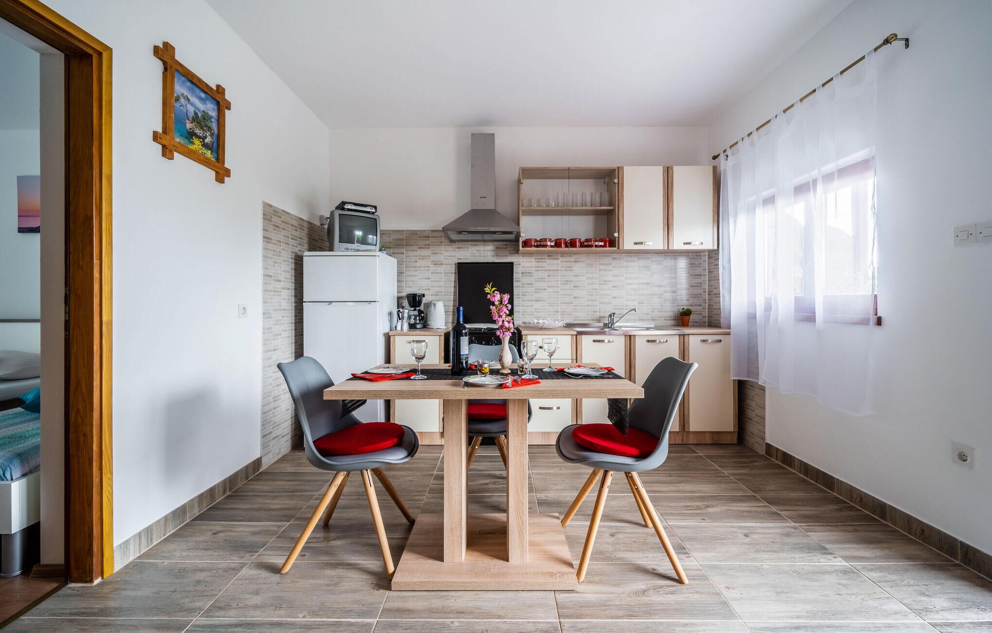 A compact kitchen with a dining area, featuring a wooden table, two chairs, and a small refrigerator.