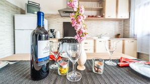 A dining table with a bottle of wine, glasses, and a vase with flowers.