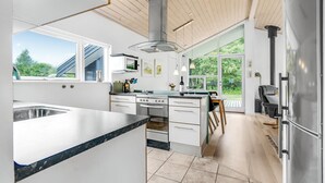A modern kitchen with a large island, stainless steel appliances, and large windows offering a view of the outdoors. - Nice home in Asaa with kitchen (Asaa)
