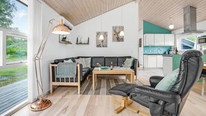 A modern living room with a sofa, a coffee table, and a dining area. There is a large window providing a view of the outdoors. - Nice home in Asaa with kitchen (Asaa)