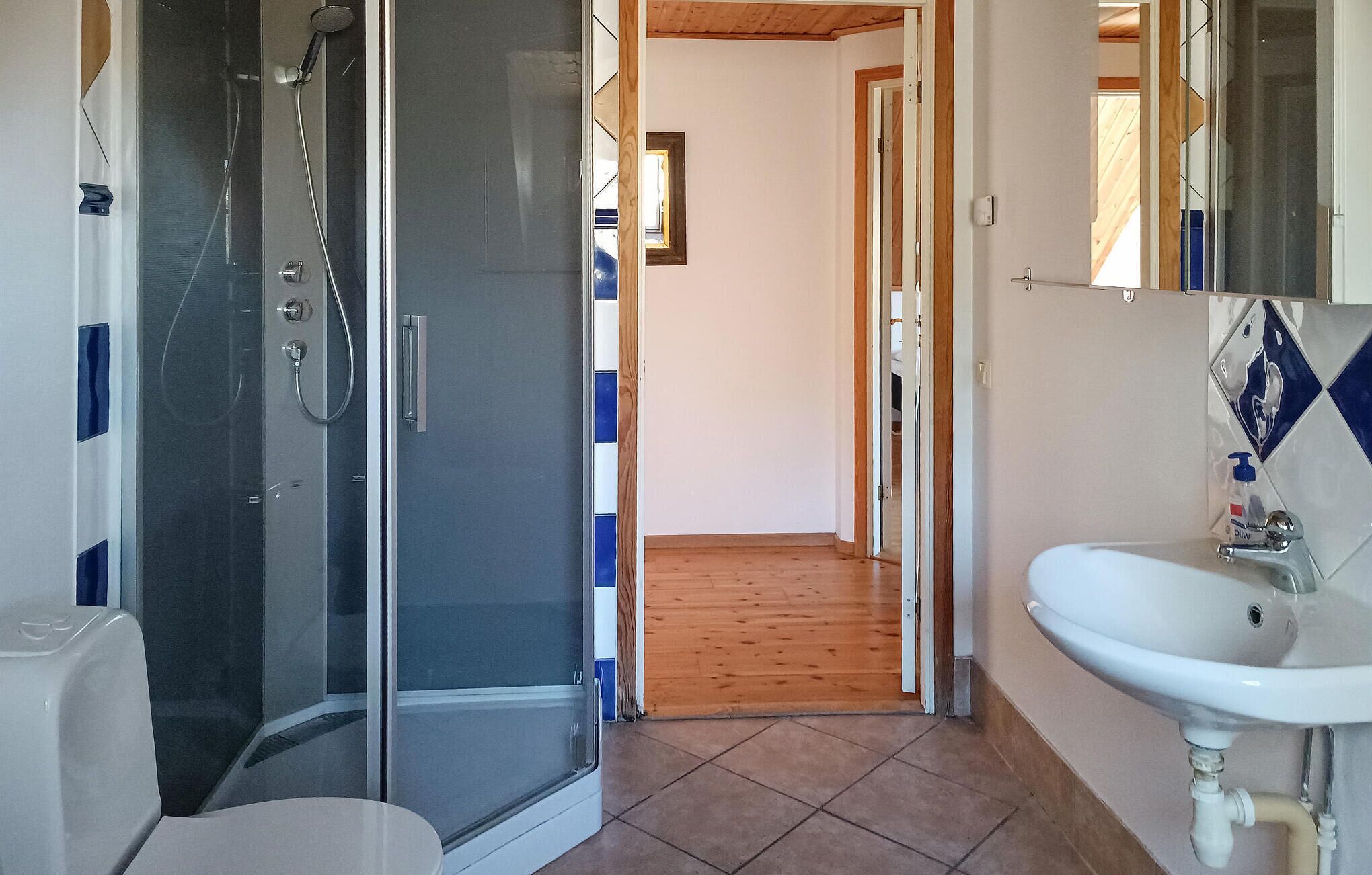 Een badkamer met een douchecabine van glas, een wastafel en een spiegel.