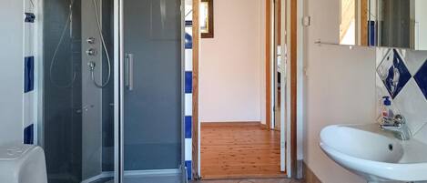Een badkamer met een douchecabine van glas, een wastafel en een spiegel.