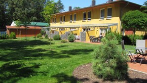 A yellow building with a patio area, outdoor seating, and a well-maintained lawn.