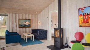 A cozy room with a wooden interior, a sofa, a table, a painting, and a fireplace. - Stunning home in Knebel (Knebel)