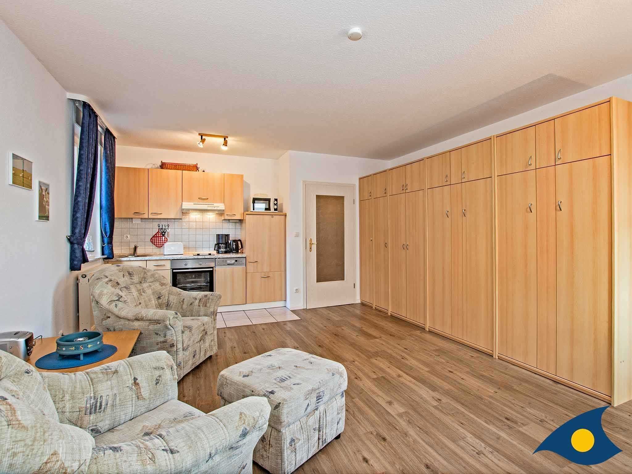 Un espacio habitable compacto con kitchenette, sofá, mesa de comedor y armario.
