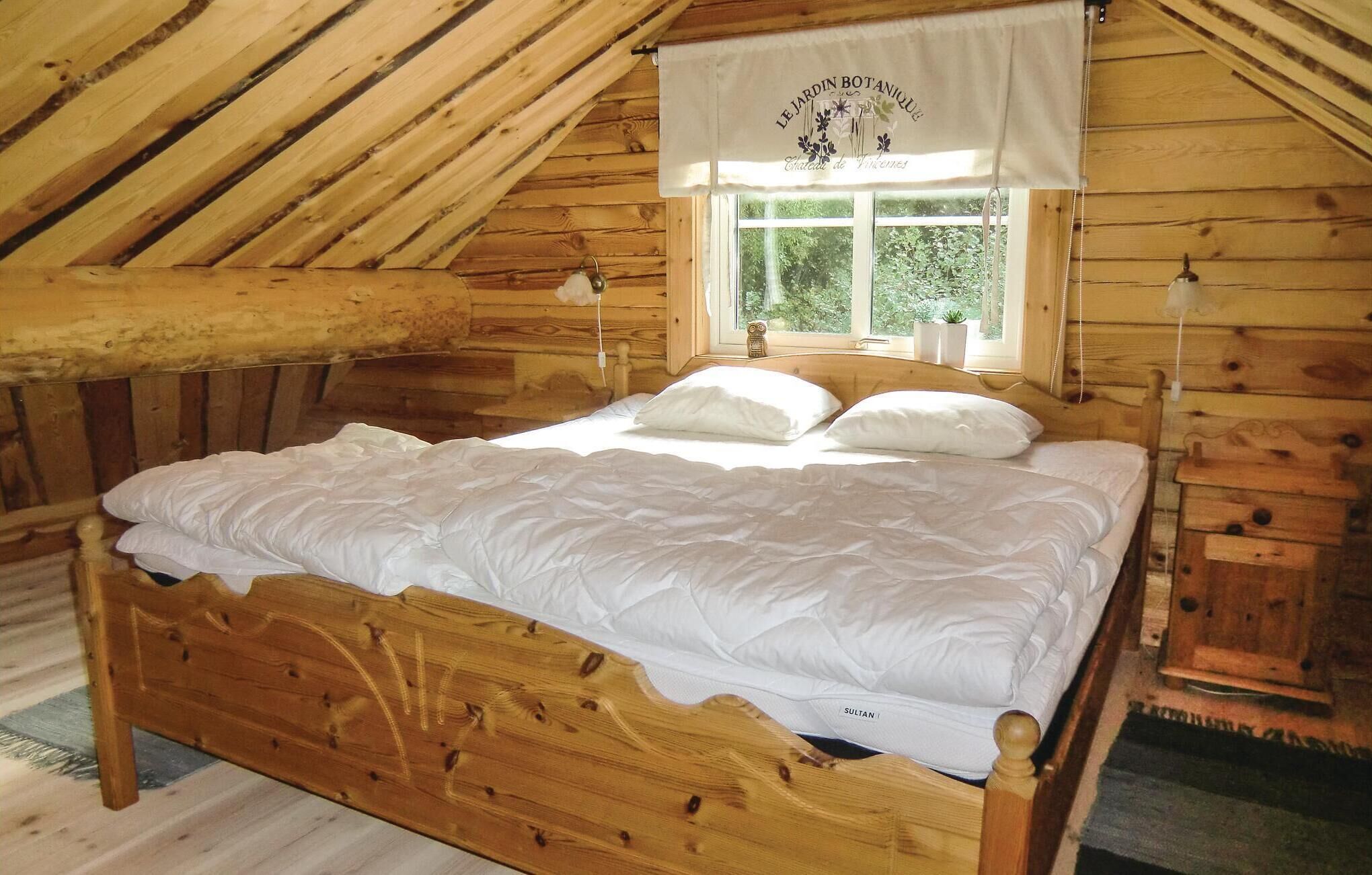 A wooden bed in a cabin with a window and a curtain.