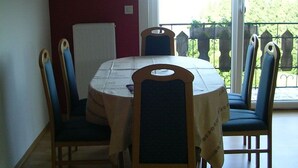 A dining area with a round table, chairs, a white tablecloth, and a view of a balcony with a railing. - DZ 5 - Farm Moadl (Miglberg)