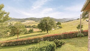 Un paysage rural avec une maison, des champs verdoyants et des collines en arrière-plan.