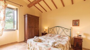 Une chambre à coucher avec un lit, une armoire en bois et une fenêtre avec des rideaux.
