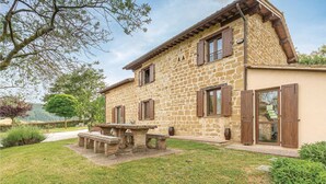 Une maison en pierre avec un balcon, une porte en bois et un petit jardin.