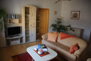 Un salon comprenant un téléviseur, un canapé, une table basse et un meuble avec des portes en verre.