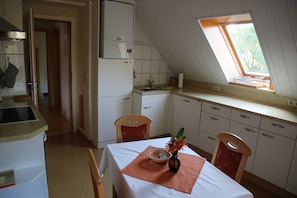 A compact kitchen with a dining area, a window with a view, and a small sink.