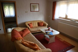 Ein Wohnzimmer mit einer Couch, einem Couchtisch und einem Fenster mit Vorhängen.