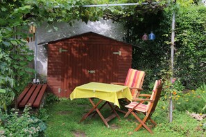 Ein hölzernes Gartenhaus mit einem gelben Tisch und zwei Stühlen.