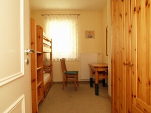 Una habitación con literas, una silla, una mesita y un radiador.