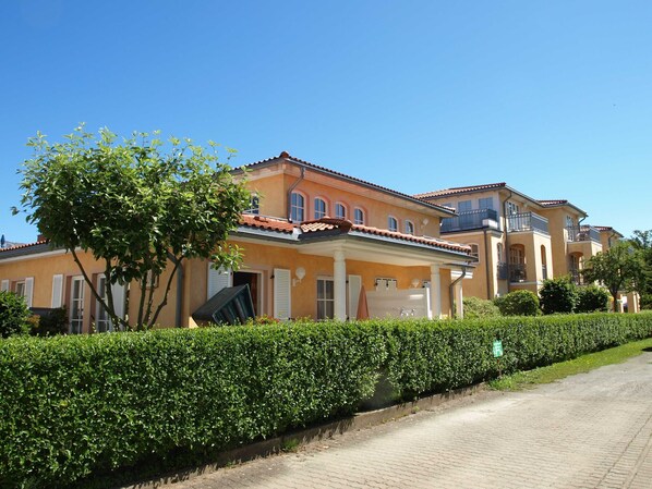 Una hilera de casas de estilo mediterráneo con un camino de entrada pavimentado y setos cuidados.