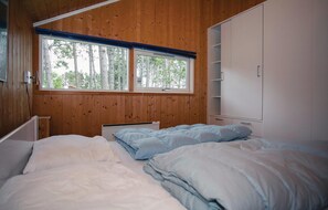 Enjoy a peaceful retreat with a view of the surrounding trees from this serene bedroom featuring a comfortable bed and ample storage.