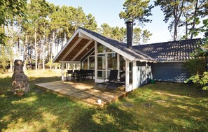 Situated in a wooded area, this cabin features a covered porch and stone fireplace.