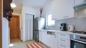 Eine moderne Küche mit Kühlschrank, Herd, Backofen und Kaffeemaschine.