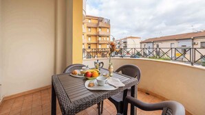 A balcony with a table set for breakfast, including fruits, pastries, and a coffee setup. - Holiday apartment with balcony and air conditioning (Alghero)
