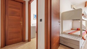 A room with a bunk bed, wooden doors, and a tiled floor. - Holiday apartment with balcony and air conditioning (Alghero)