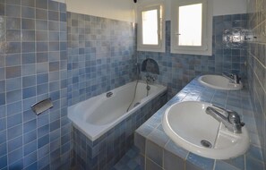 Ein Badezimmer mit einer Badewanne, einem Waschbecken und einem Fenster.
