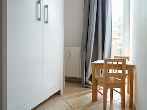 Une pièce avec une armoire blanche, une chaise en bois et un radiateur.