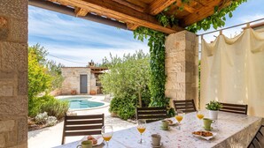 Un espace extérieur aménagé pour les repas, avec une piscine, des murs en pierre et de la verdure.