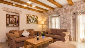 Un salon chaleureux avec deux canapés marron, une table basse en bois et un mur en pierre.