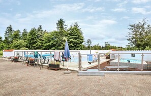A poolside area with lounge chairs, a table, and a covered seating area.